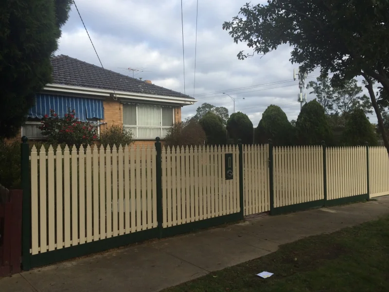 Cream steel picket fence with green posts and bottom rail